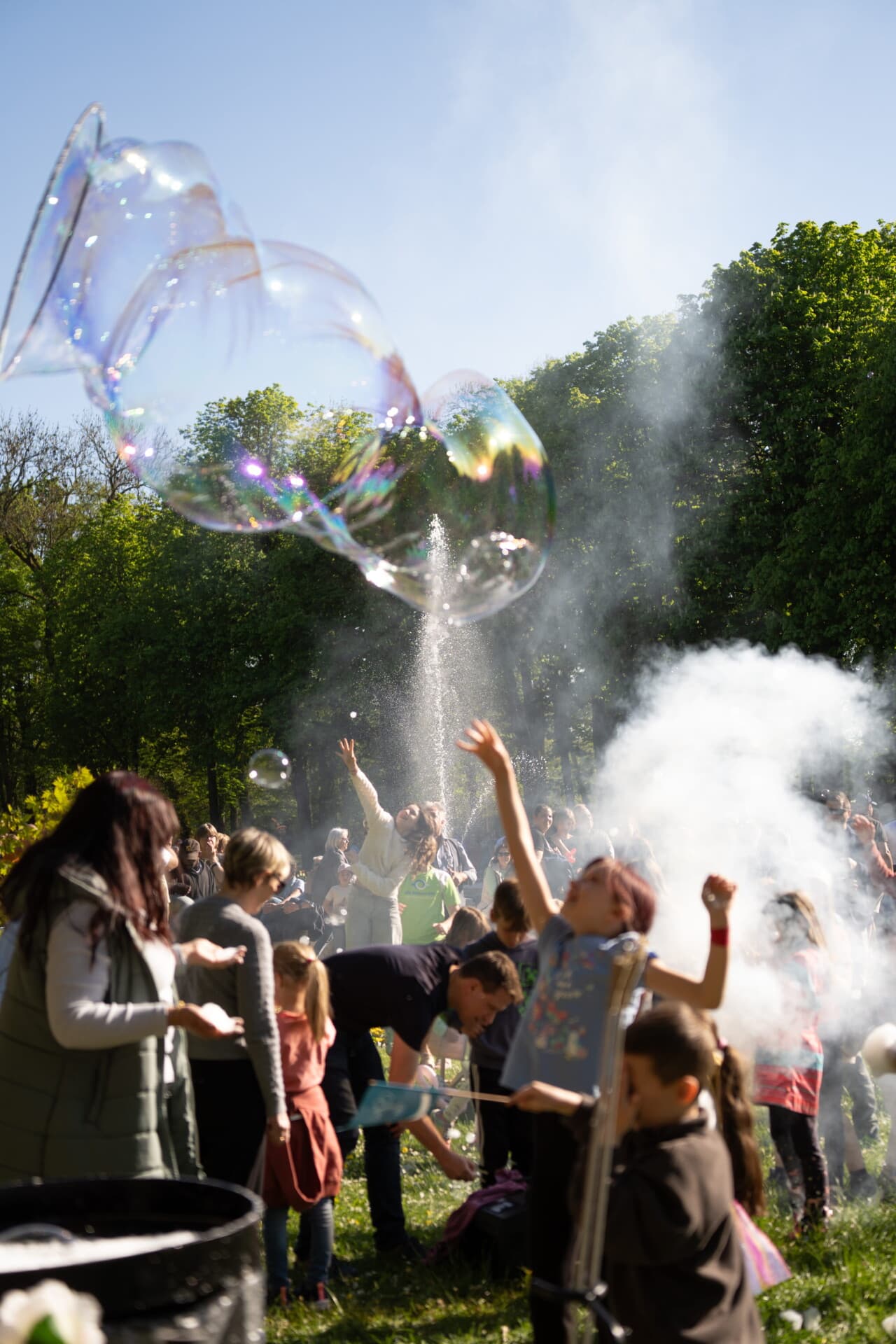 Kinder greifen bei einem Fest im Kurpark nach großen Seifenblasen