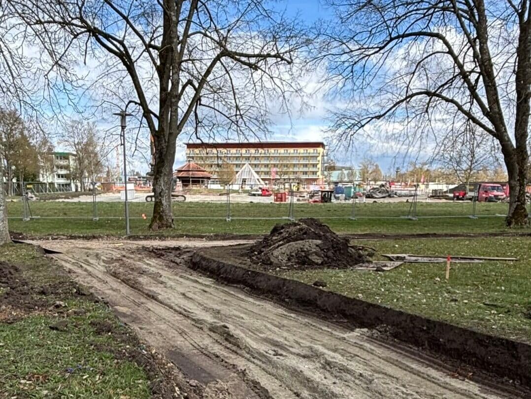 Aufgerissener Parkweg im Kurpark zwischen kahlen Bäumen, im Hintergrund die Baustelle