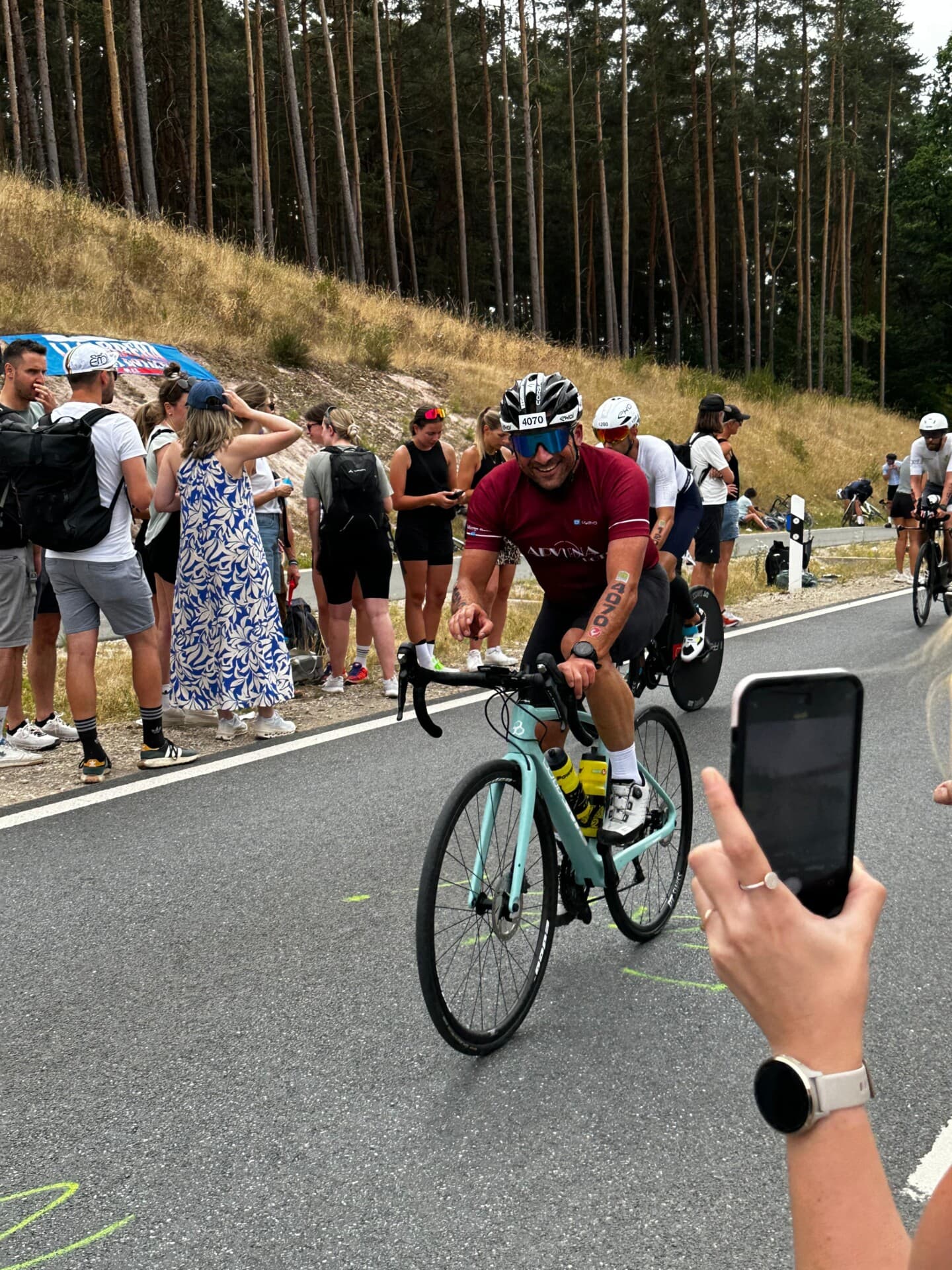 Triathlet auf dem Rennrad auf der Strecke, am Straßenrand Zuschauer