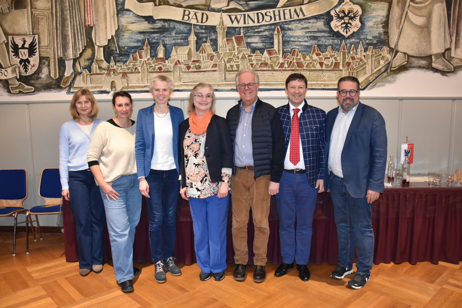 Sieben Personen vor einem historischen Wandbild von Bad Windsheim im Sitzungssaal